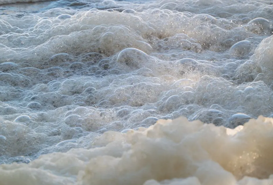 Detailed view of ocean foam and bubbles forming on the water surface.